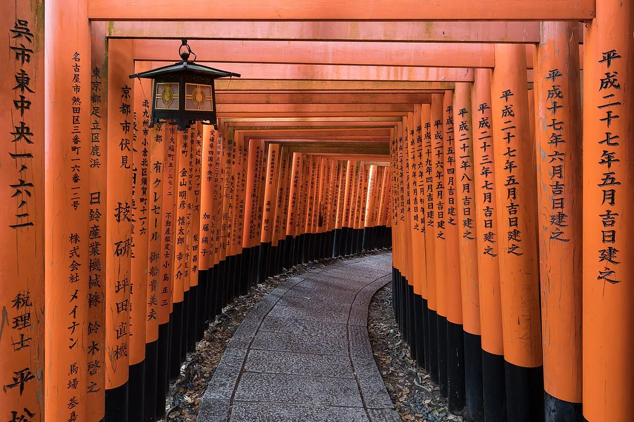 Torii path with a hanging lantern at Fushimi Inari Taisha Shrine Senbontorii, Kyoto , Japan .