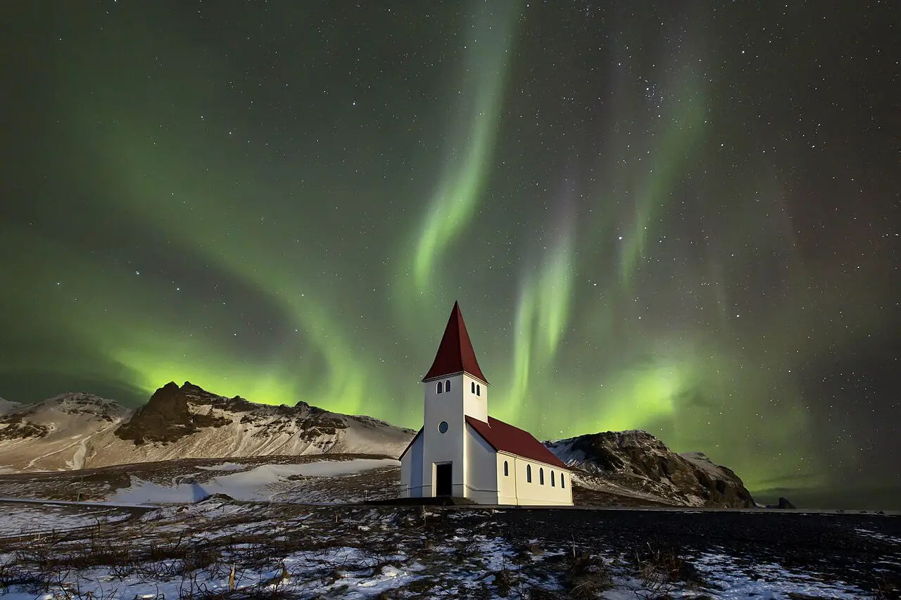 Photomontage - The Víkurkirkja church at Vik in Iceland on a clear night. The aurora was shot separately in Iceland (see File:Flames in the