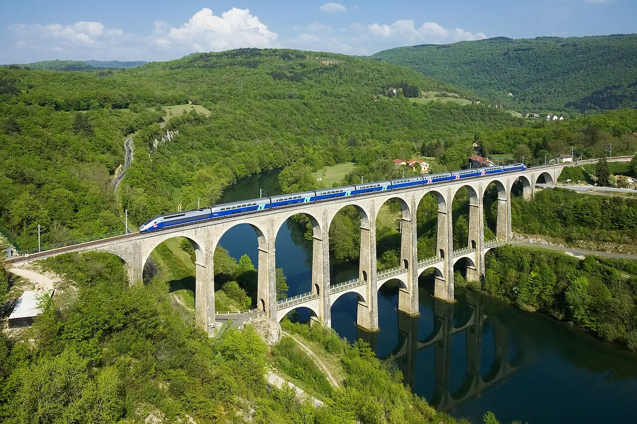 A SNCF TGV Duplex trainset is crossing the Cize - Bolozon viaduct over the Ain river. The viaduct is part of the Haut-Bugey line, which was