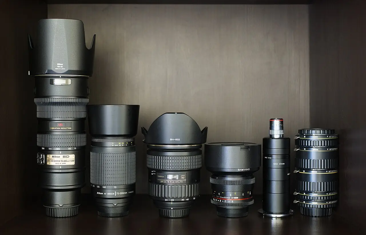 Photographic lenses and tubes with wooden background, from left to right: Nikon AF-S VR Zoom-Nikkor 70-200mm f/2.8G IF-ED Nikon AF Zoom-Nikk